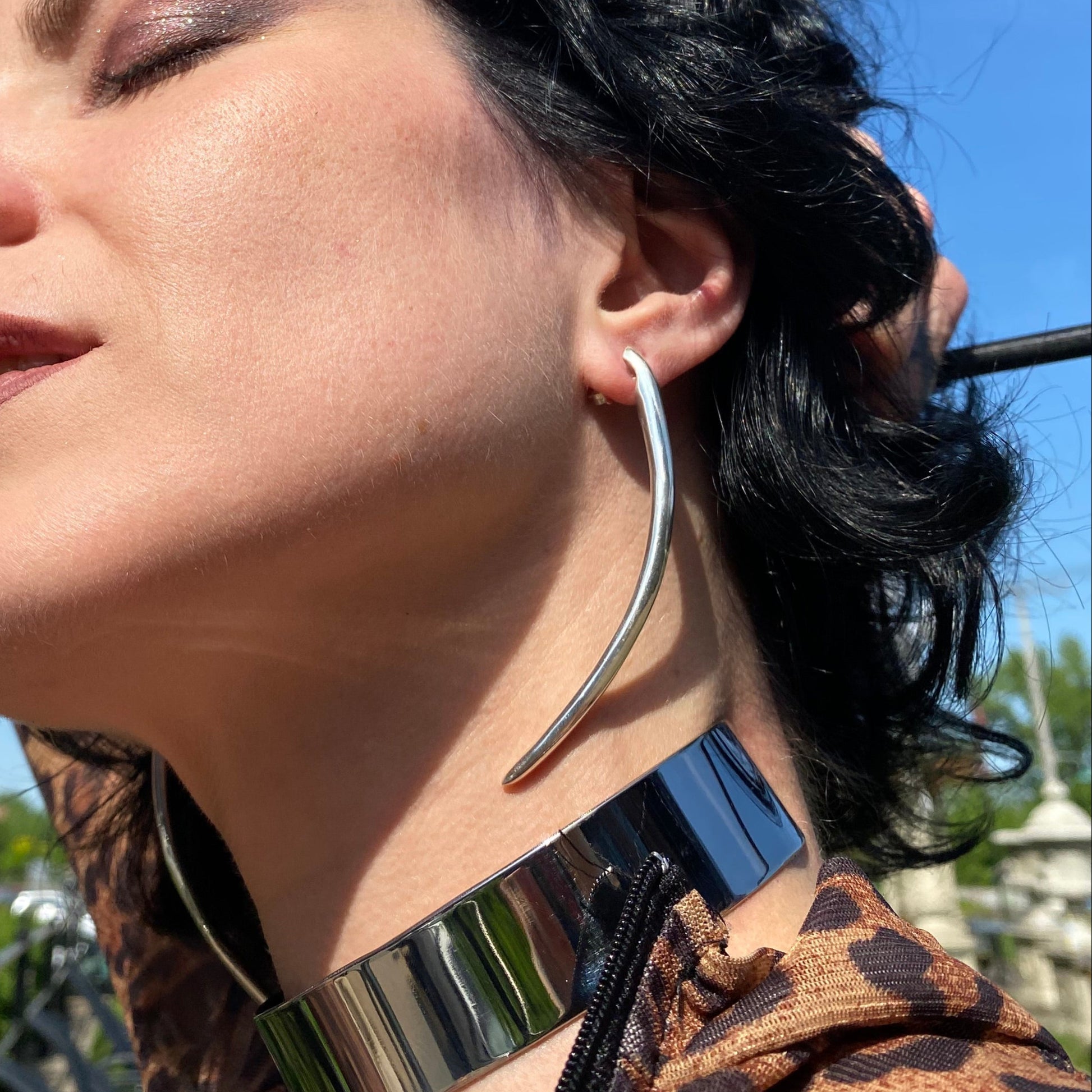 Long minimalist sterling silver curved spike earrings on a dominatrix.