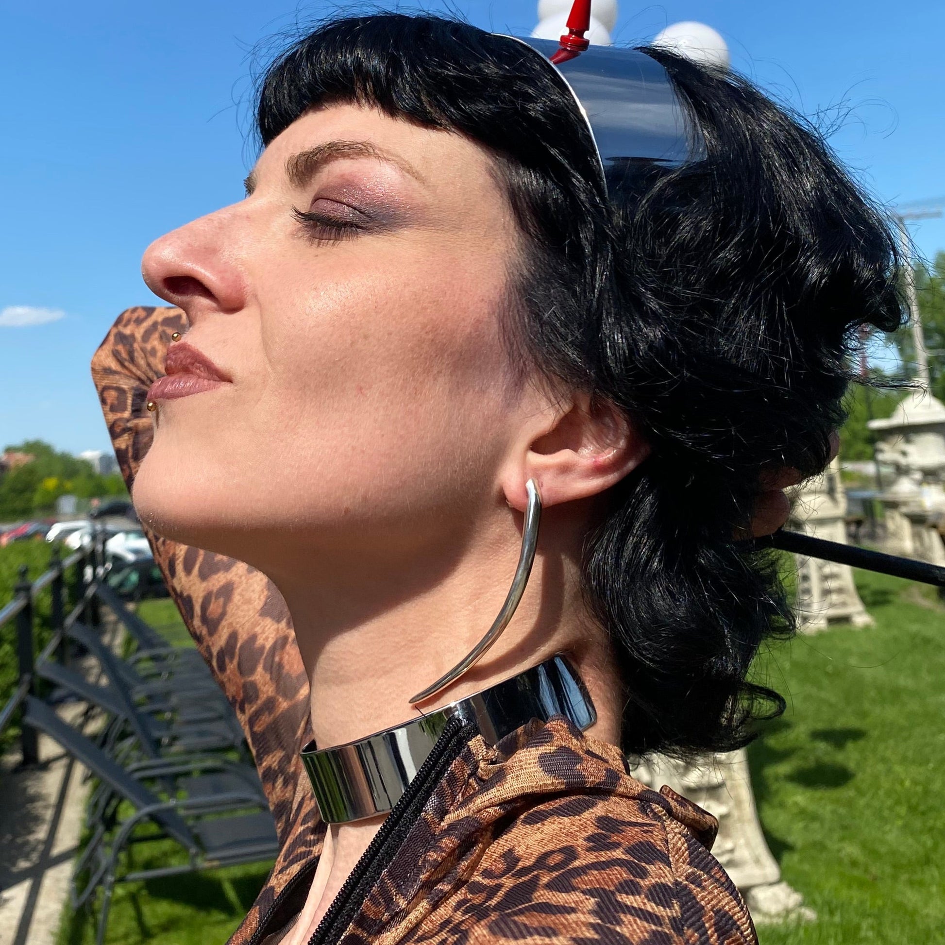 Long minimalist sterling silver curved spike earrings on a dominatrix.